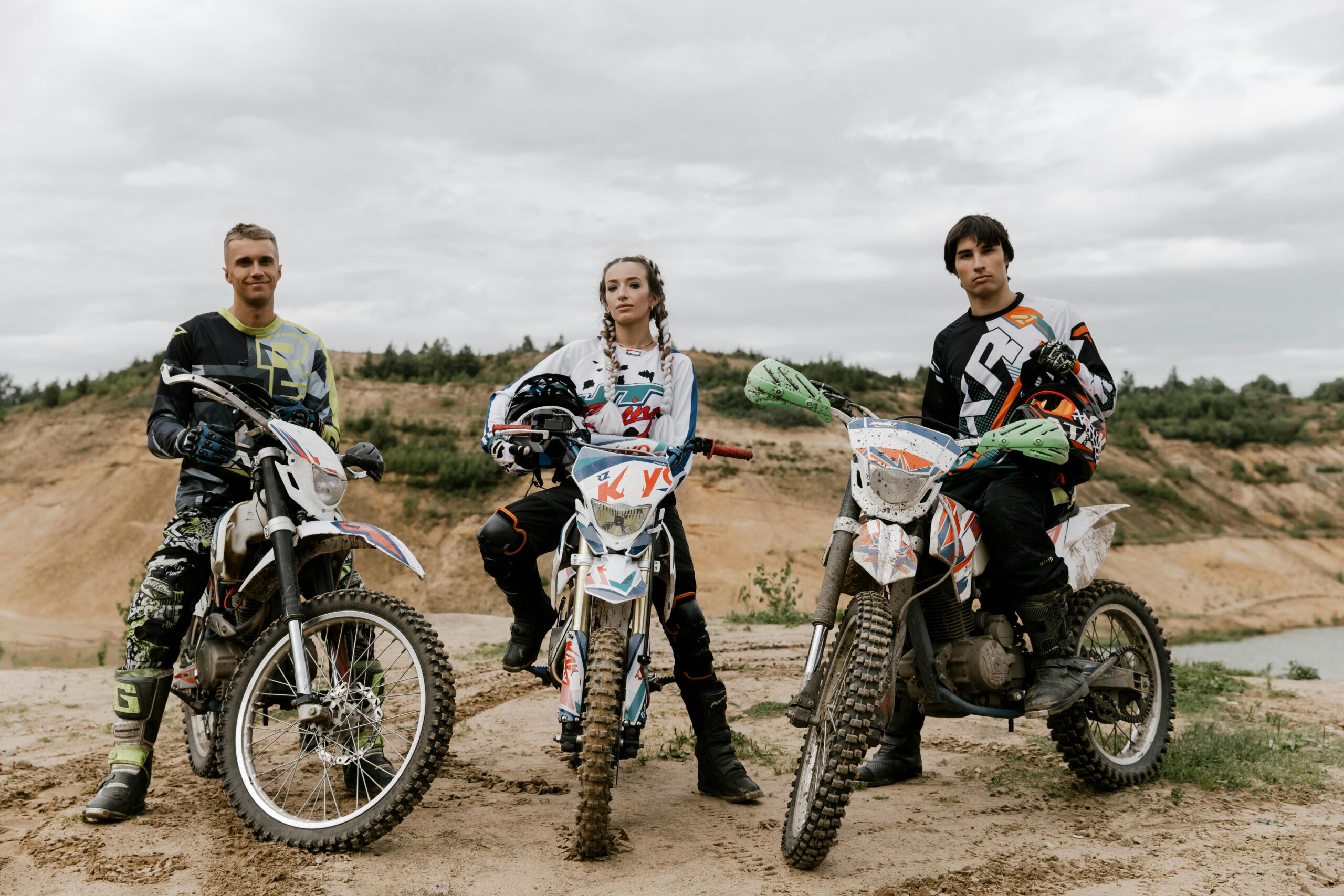Three friends pose with their dirt bikes ready for an off-road motocross adventure.